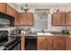 Traditional kitchen featuring wooden cabinets, black appliances, and a window over the sink at 5 N 87Th Ln, Tolleson, AZ 85353