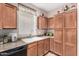 Traditional kitchen featuring wooden cabinets, black appliances, and a window over the sink at 5 N 87Th Ln, Tolleson, AZ 85353