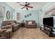 Cozy living room with plush sofas, ceiling fan, neutral tile flooring, and bright light at 5 N 87Th Ln, Tolleson, AZ 85353