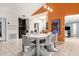 Dining area featuring a modern white table, orange accent wall, and neutral flooring at 9389 N 87Th Way, Scottsdale, AZ 85258