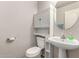 Cozy half bath with a pedestal sink, oval mirror, and a built in toilet and cabinet combination at 12026 W Salter Dr, Sun City, AZ 85373