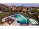 Aerial view showcasing the backyard's pool, patio, lush landscaping, and surrounding neighborhood with mountain views at 13631 E Windrose Dr, Scottsdale, AZ 85259