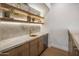Stylish bar area with marble countertops, floating shelves, gold faucet, and a mini beverage cooler for entertaining at 13631 E Windrose Dr, Scottsdale, AZ 85259