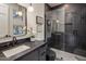 Modern bathroom featuring dark tiling, a glass shower, and unique light fixtures at 13631 E Windrose Dr, Scottsdale, AZ 85259