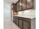 Well-lit kitchen with dark cabinets, white countertops, and modern under-cabinet lighting for a luxurious feel at 15349 W Cottontail Ln, Surprise, AZ 85387