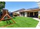 Spacious backyard with artificial grass, patio seating, play structure, and mature landscaping at 17937 W Westpark Blvd, Surprise, AZ 85388