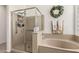 This bathroom features a clear glass shower, a drop-in tub, and decorative towels at 17937 W Westpark Blvd, Surprise, AZ 85388