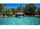 Crystal-clear pool featuring a rock waterfall, surrounded by lush tropical foliage and sparkling blue water at 2101 S 167Th Dr, Goodyear, AZ 85338