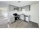 Modern kitchen with stainless steel appliances, light gray cabinets, white countertops, and gray wood-look floors at 2724 W Highland Ave, Phoenix, AZ 85017