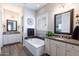 Bathroom with double sinks, granite countertops, a soaking tub, and wood-look floors at 31311 N 138Th Ave, Peoria, AZ 85383