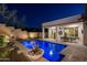 Backyard view of pool, covered patio, and landscaped yard with decorative planters lit in the evening at 31311 N 138Th Ave, Peoria, AZ 85383