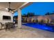Inviting backyard pool and patio with outdoor kitchen, seating, and water feature wall illuminated in the evening at 31311 N 138Th Ave, Peoria, AZ 85383