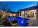 Backyard view of the pool, covered patio, and landscaped yard with decorative planters lit in the evening at 31311 N 138Th Ave, Peoria, AZ 85383