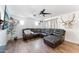 Bright living room featuring dark wood-look floors, a ceiling fan and a comfortable reclining sectional at 3508 E Gelding Dr, Phoenix, AZ 85032