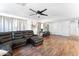 Bright living room featuring dark wood-look floors, a ceiling fan and a comfortable reclining sectional at 3508 E Gelding Dr, Phoenix, AZ 85032