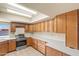 Well-lit kitchen showcasing wood cabinets, tile flooring, stainless steel appliances, and bright lighting at 3747 W Aire Libre Ave, Phoenix, AZ 85053