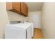 Functional laundry room features washer, dryer, wood cabinets, and patterned tile flooring at 3747 W Aire Libre Ave, Phoenix, AZ 85053