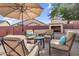 Relaxing backyard with comfortable seating arrangement around an outdoor fireplace and large shade umbrella at 4821 E Kirkland Rd, Phoenix, AZ 85054