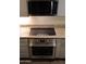 Close-up of stainless steel oven and induction cooktop installed below the microwave and granite countertop at 5720 S 21St Ter, Phoenix, AZ 85040
