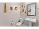 Bright powder room featuring a pedestal sink, toilet, mirror and unique decorative wall art at 6948 E Quill St, Mesa, AZ 85207