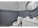 Charming powder room with stylish wainscoting, patterned wallpaper and a round mirror at 7601 E Roosevelt St # 1012, Scottsdale, AZ 85257
