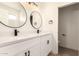 Modern bathroom boasts dual sinks, white cabinets with black hardware, and a stylish lighting fixture at 8928 E Crescent Ave, Mesa, AZ 85208