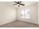 Bright bedroom with neutral carpet, a ceiling fan, and a window offering an outdoor view at 8928 E Crescent Ave, Mesa, AZ 85208