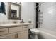 Modern bathroom featuring a sleek vanity, decorative mirror, and a combination shower and tub with stylish tile at 1027 E El Camino Dr, Phoenix, AZ 85020
