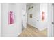 Hallway with white walls, light wood floors and colorful art at 10951 E Delta Ave, Mesa, AZ 85208