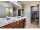 Bathroom featuring a double sink vanity, large mirror, and walk-in closet at 13585 N 87Th Dr, Peoria, AZ 85381