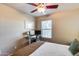 Comfortable bedroom features a ceiling fan, a window for natural light, and a cozy study area at 13585 N 87Th Dr, Peoria, AZ 85381