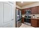 Well-equipped kitchen with stainless steel appliances, dark wood cabinets, and tiled floors at 13585 N 87Th Dr, Peoria, AZ 85381