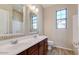 This bathroom features double sinks, wooden cabinets, large mirrors, and a window at 15105 W Glenrosa Ave, Goodyear, AZ 85395