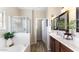 Bright bathroom featuring a shower, tub, double sinks, and wood look floors at 15105 W Glenrosa Ave, Goodyear, AZ 85395