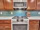 Close up of stainless steel gas range and built-in microwave, complemented by stylish tile backsplash and wood cabinets at 15817 S 177Th Dr, Goodyear, AZ 85338