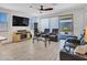 Bright living room featuring comfortable leather seating, tile floors, a ceiling fan and a large tv for entertainment at 15817 S 177Th Dr, Goodyear, AZ 85338
