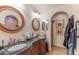 A primary bath with dual sinks, a custom vanity, and an arched doorway leading to a walk-in shower at 1702 W Monterosa W St, Phoenix, AZ 85015