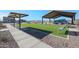 Grassy area with playground, shade structure, picnic tables, and benches in common community area at 17373 W Jessie Ln, Surprise, AZ 85387