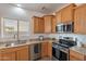 Kitchen area with stainless steel appliances, modern sink, and wood cabinetry with natural light at 17844 W Caribbean Ln, Surprise, AZ 85388