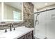 The bathroom showcases a stone accent wall, updated vanity, and walk-in shower with glass door at 18233 N 55Th Dr, Glendale, AZ 85308