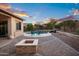 Serene backyard with sparkling pool, two blue chairs, landscaped surroundings, and a fire pit at 18544 W Devonshire Ave, Goodyear, AZ 85395