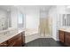 Bright bathroom featuring a soaking tub, glass-enclosed shower, and double vanity sinks at 18544 W Devonshire Ave, Goodyear, AZ 85395