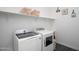 Bright laundry room featuring a front-loading washer and dryer, shelving, and tiled floor at 18544 W Devonshire Ave, Goodyear, AZ 85395