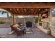 Inviting outdoor space with covered patio, stone fireplace, tv, grill, and comfortable seating at 18544 W Devonshire Ave, Goodyear, AZ 85395