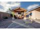 Inviting outdoor living space featuring a covered patio, stone fireplace, outdoor kitchen and comfortable seating area at 18544 W Devonshire Ave, Goodyear, AZ 85395