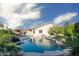 Backyard oasis featuring a sparkling pool, covered patio, lush landscaping, and expansive lawn area at 18544 W Devonshire Ave, Goodyear, AZ 85395