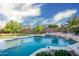 A backyard swimming pool with a rock waterfall feature, lush landscaping and a peek at the covered patio at 18544 W Devonshire Ave, Goodyear, AZ 85395