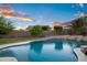Large swimming pool surrounded by lush landscaping and a privacy fence at dusk at 18544 W Devonshire Ave, Goodyear, AZ 85395