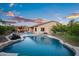 Backyard view featuring a pool, covered outdoor living area, and beautiful landscaping at dusk at 18544 W Devonshire Ave, Goodyear, AZ 85395