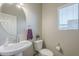 Cozy half bathroom featuring a pedestal sink, toilet, a round mirror, and a window with blinds at 18811 E Pelican Ct, Queen Creek, AZ 85142